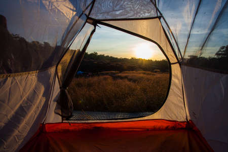 women sit front of tent with sunriseの写真素材