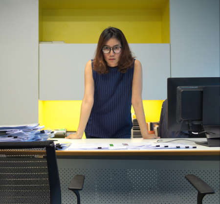 Lady boss in anger mood standing by her deskの写真素材
