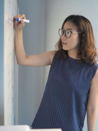 Smart and beautiful lady writing on the white boardの写真素材