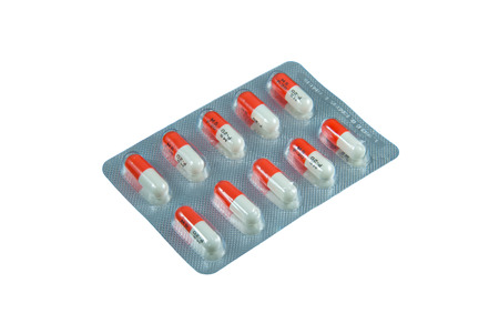 Single tablet of orange and white capsules isolated in white backgroundの写真素材