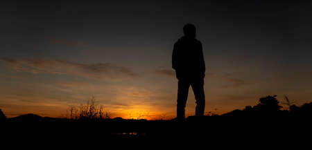 Silhouette of a man standing at sunsetの写真素材