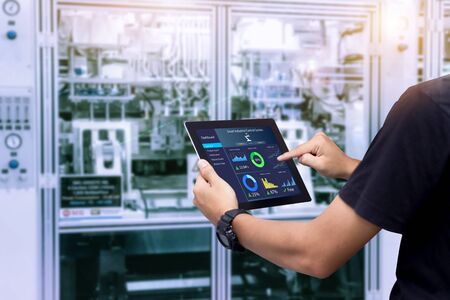Smart industry control concept.Hands holding tablet on blurred automation machine as backgroundの写真素材