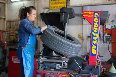 PHITSANULOK, THAILAND - DECEMBER 29 , 2016 :  Professional auto mechanic replacing tire on wheel in car repair workshop in Phitsanulok, Thailandのeditorial素材