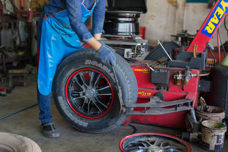 PHITSANULOK, THAILAND - DECEMBER 29 , 2016 :  Professional auto mechanic replacing tire on wheel in car repair workshop in Phitsanulok, Thailandのeditorial素材