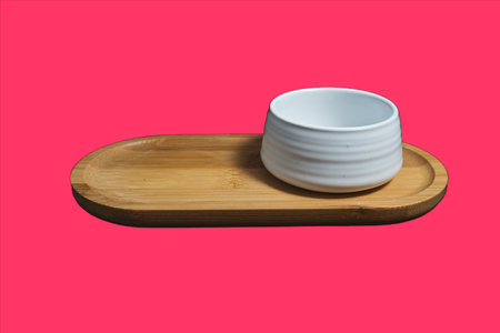 Isolated Ceramic mug of tea, made of white clay, on a wooden plate on pink background.の写真素材