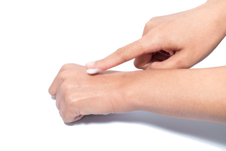 Closeup woman applying protective cream on hands. Cold season and dry air, applying lotion for preventing dry skin. Isolation in white backgroundの写真素材