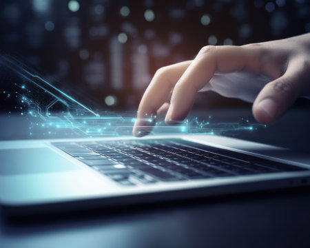 Close up of hand using laptop with glowing business interface on dark backgroundの素材