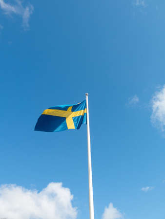 Swedish flag blowing in the wind on the blue skyの写真素材