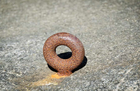 one rusty mooring loop for boat on the rockの写真素材