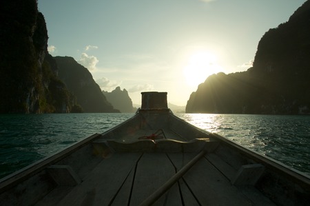 Traveling by wooden boat surrounded by cliff and mountain in a lake.の写真素材