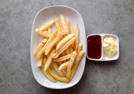french fries with tomato sauce and mayonnaise on the tableの写真素材