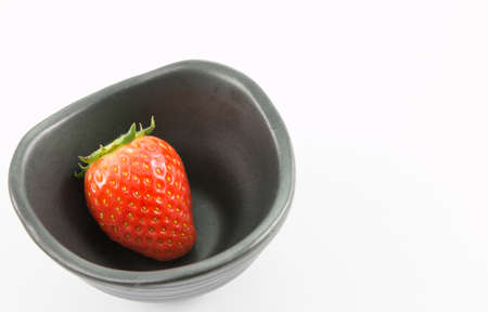 red strawberry in black chalice on white backgroundの写真素材
