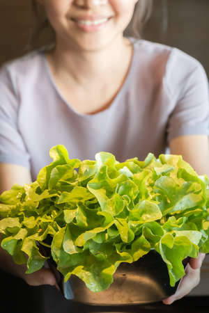 organic vegetables in chalice with asian women in backgroundの写真素材