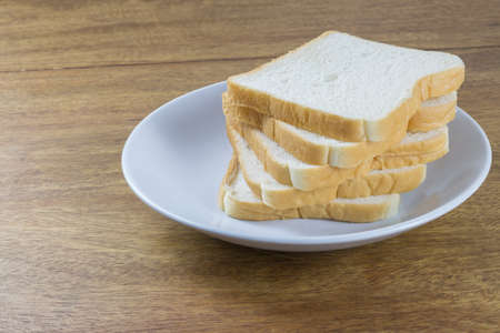 sliced of bread in white plate, on wood tableの写真素材