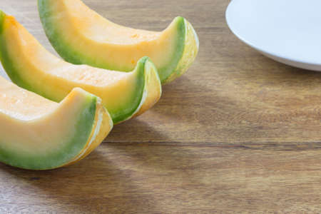 sliced muskmelon on wood table with white plate decorationの写真素材