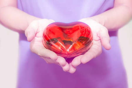 woman's hand holding plastic red heart shape with chocolate insideの写真素材