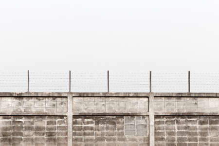 barbed wire above old concrete fence with muddy sky