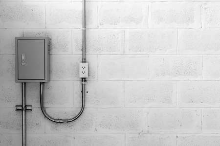 electric box on concrete wall with steel tube and plug, black and white