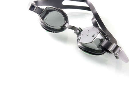 black swimming glasses on white background with water drop and shadow reflex, selective focus
