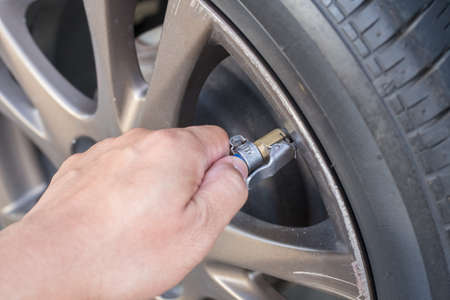 hand holding air pressure wire from air pump to vehicle tire