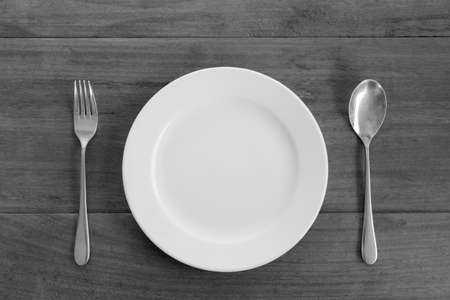 white plate, spoon and fork on wood table, black and white toneの写真素材
