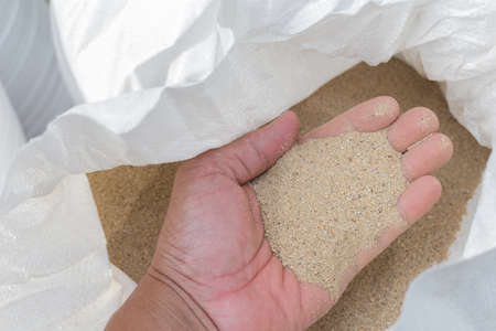 hand holding construction fine sand  in white bagの写真素材