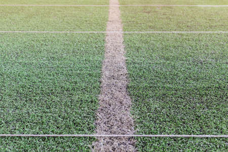 artificial green grass with charcoal grain and white line abstract background, sunlight from above, selective focusの写真素材