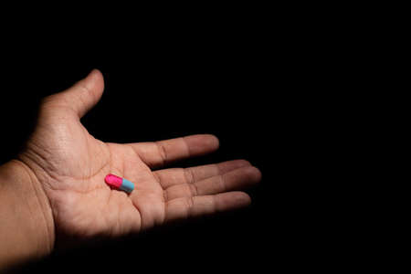 hand holding pill of capsule isolated on black backgroundの写真素材