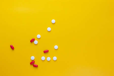 red and white pills on yellow background, medication conceptの写真素材