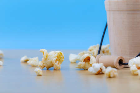 popcorn on wood table with wood bowl and blue background, selective focus