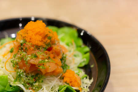 salmon salad spicy with orange shrimp eggs on green leaves, selective focus