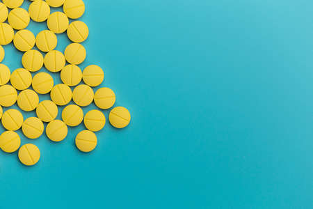 yellow pills on blue background, health care and medical conceptの写真素材