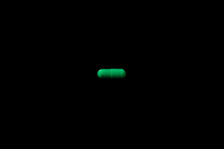 green pills capsule on black bakcground, medical health care concept