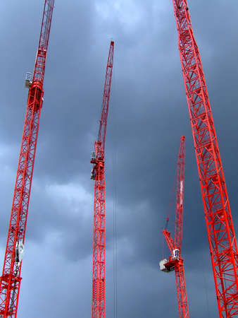 Four tall red cranes with sky in background
