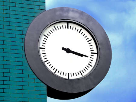 Public clock on the edge of turquoise brick wallの写真素材