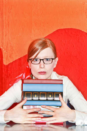 Young blonde girl with eyeglasses and bunch of booksの写真素材