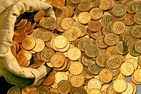 Bunch of golden coins scattered from sackの写真素材