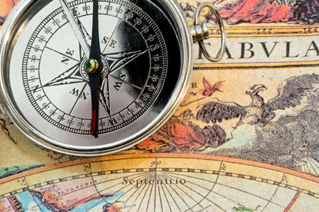 Silver metal compass on the old map