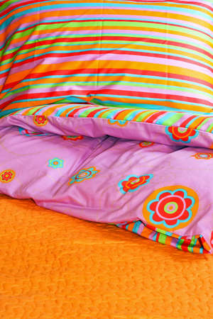 Bunch of pillows and colorful sheets over bed