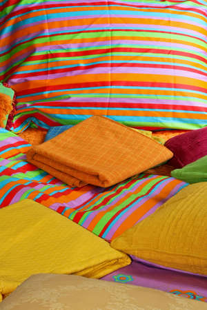 Bunch of pillows and colorful sheets over bed