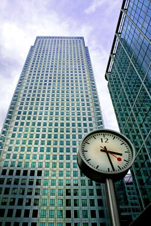 Big clock in front of two business buildingsの写真素材