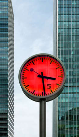 Big clock in front of two business buildingsの写真素材