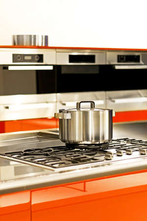 Stainless steel pot at stove in red kitchenの写真素材