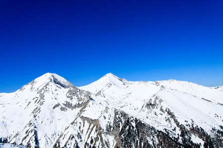 Sunny mountain peak covered in snow at winterの写真素材