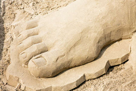 Big foot sculpture in sand at beachの写真素材