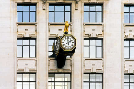 Public clock with owl statue at wall