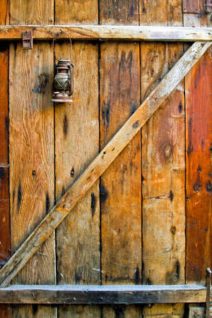 Old wooden door with mousetrap and oil lampの写真素材