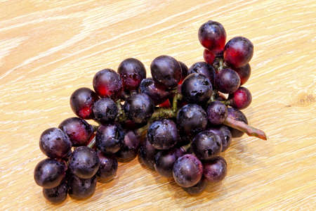 Fresh organic red grapes on wooden tableの写真素材