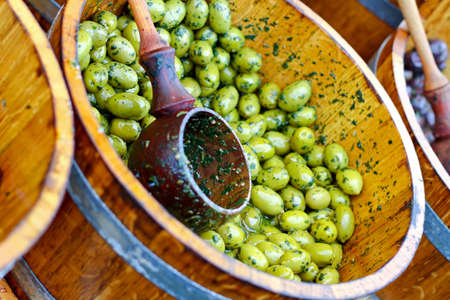 Green olives in wooden bucket sold on marketの写真素材
