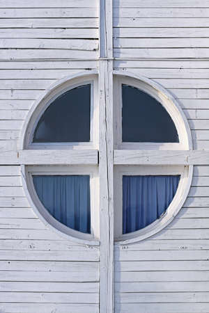 Round cross window at white wood cabin house